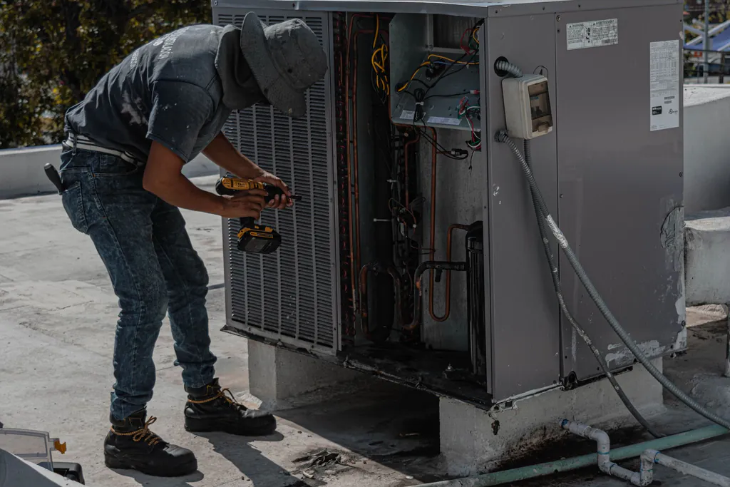 A tech working on an open rooftop condensing unit, with the rating plate that holds the model and serial numbers on its side panel
